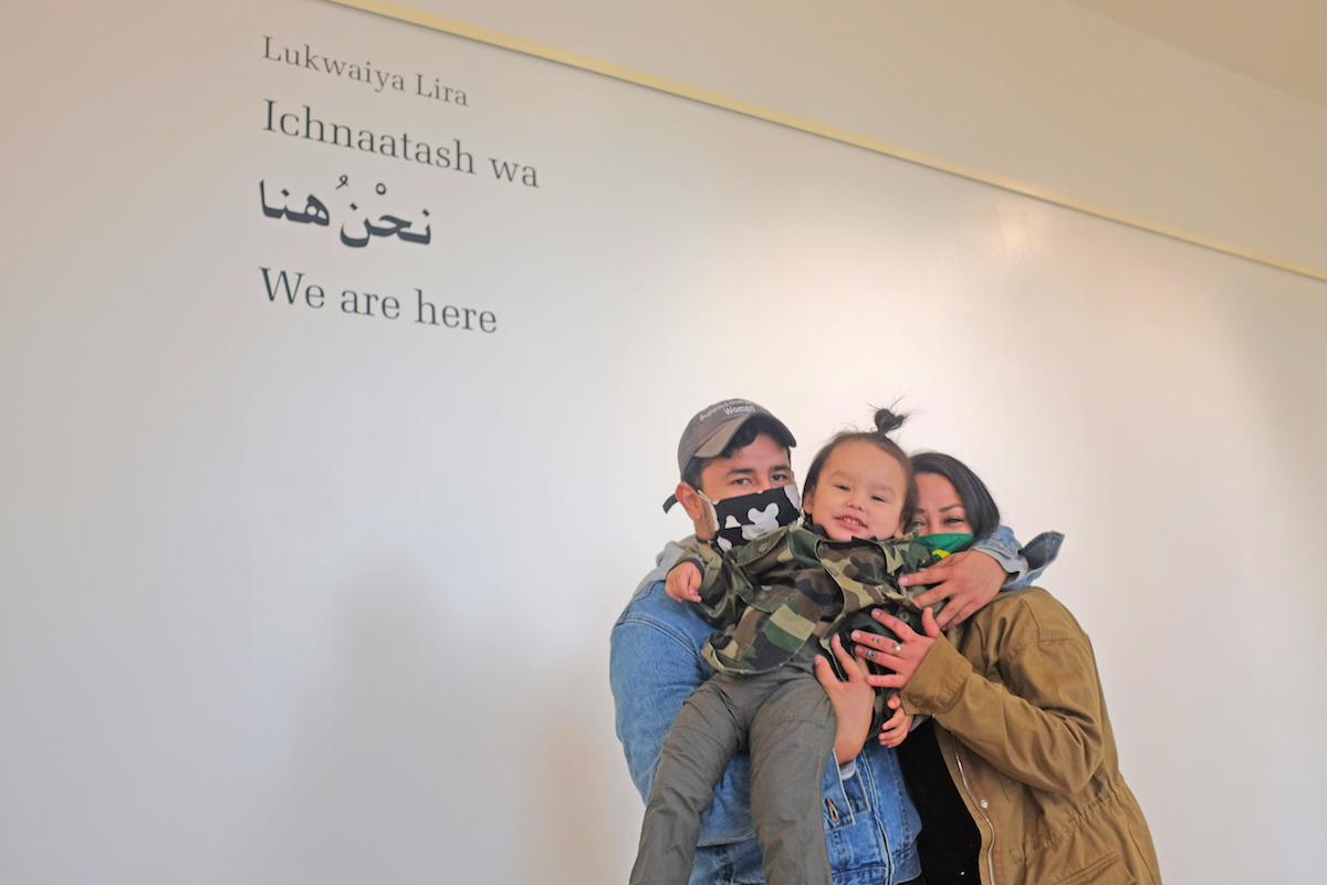 Carina Miller (right) and her partner, Lúkwaiya Lira, hold their son, Waluxpykee Walter Miller, at a gallery featuring Lúkwaiya's photo exhibition "Ichnaatash wa."